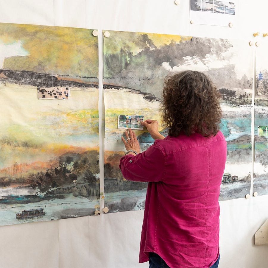 Photo taken from the back, Nina Pryde is pasting the photo onto the artwork.