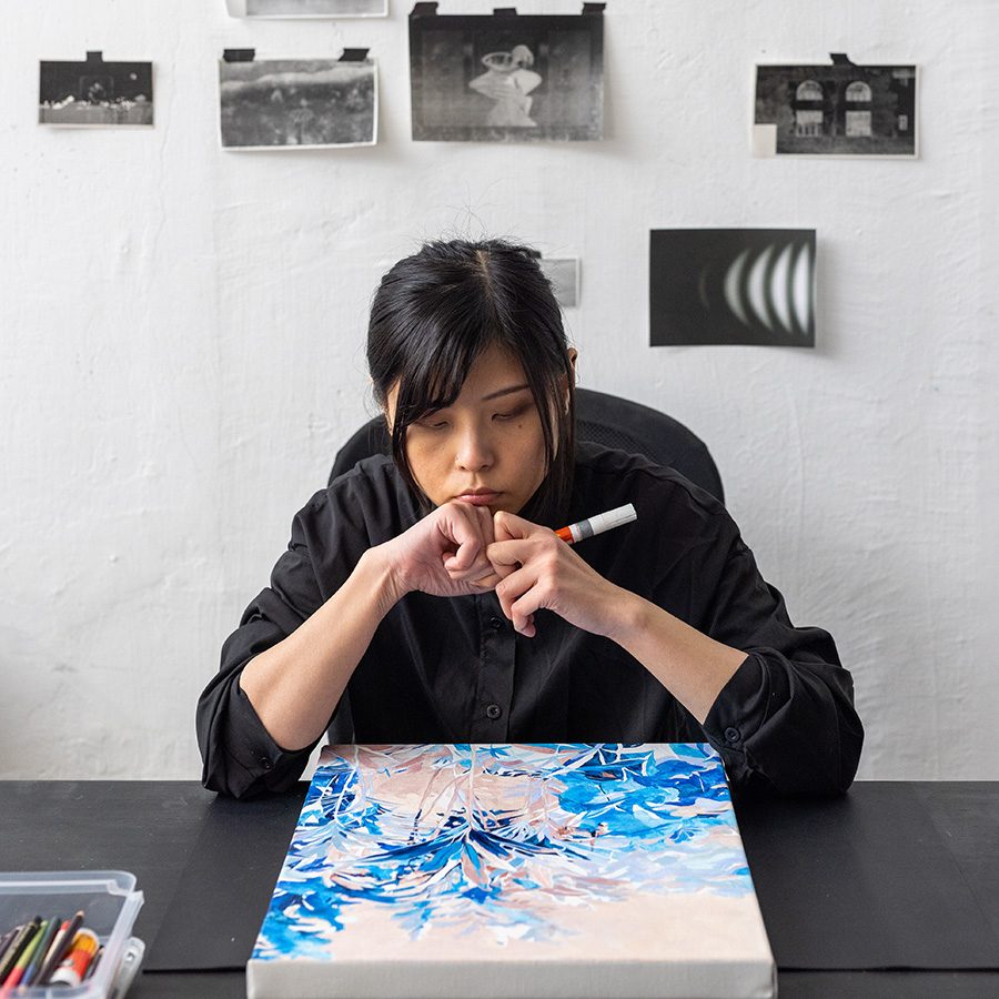 Artist Tobe Kan thinking while looking at her painting on canvas