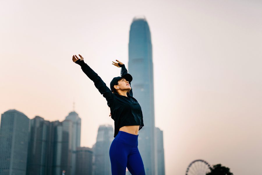 An Asian sporty woman is stretching her arms