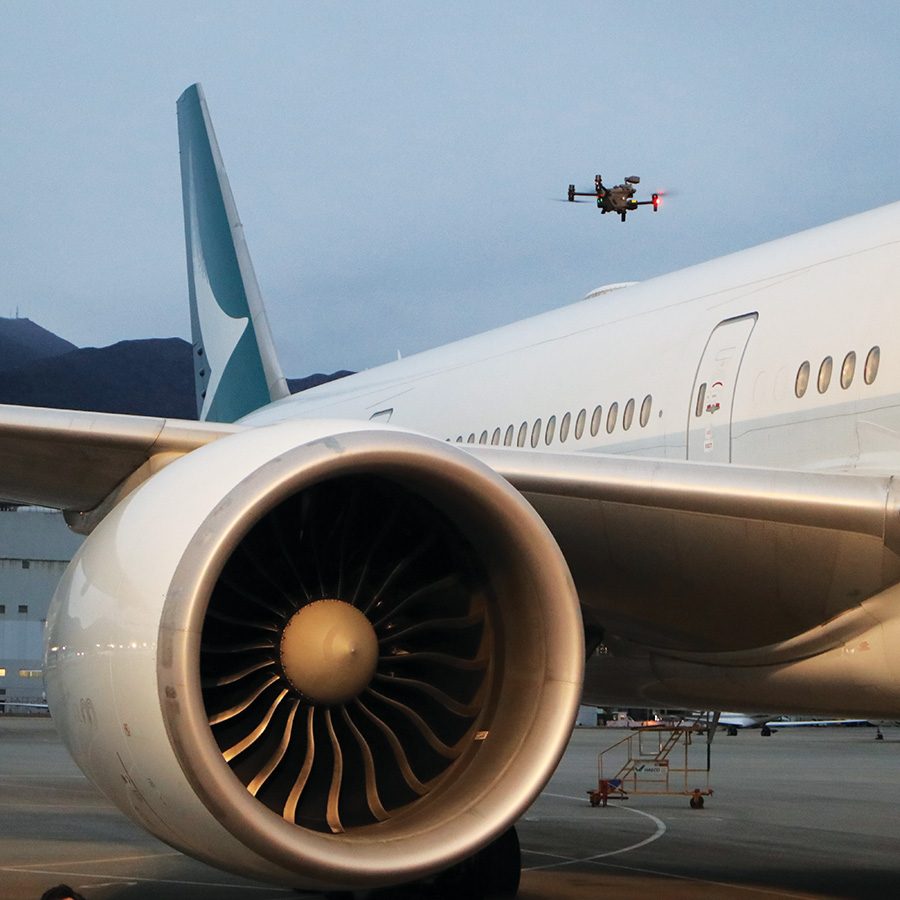Cathay Pacific aircraft wing engine with drone flying overhead