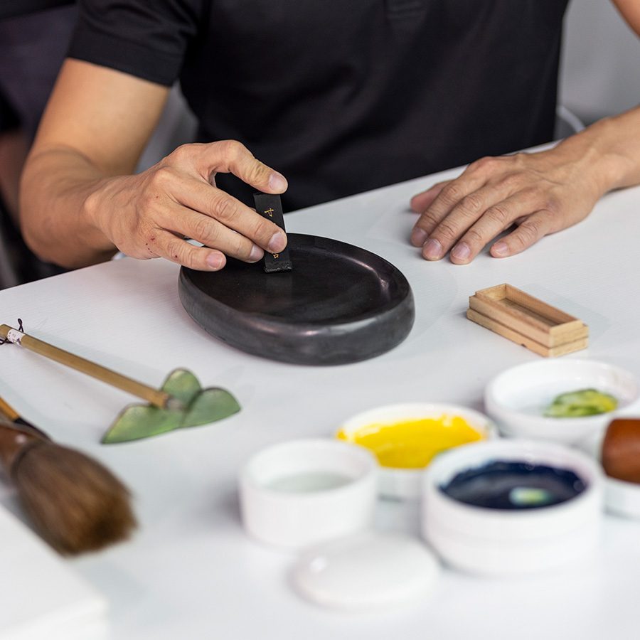 The photo highlights Koon Wai Bong's hands as he paints.