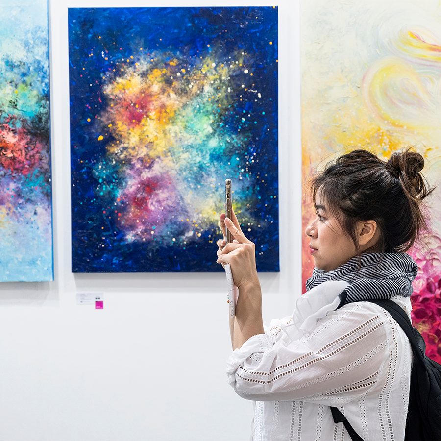 Woman taking photo of art at Affordable Art Fair, Hong Kong