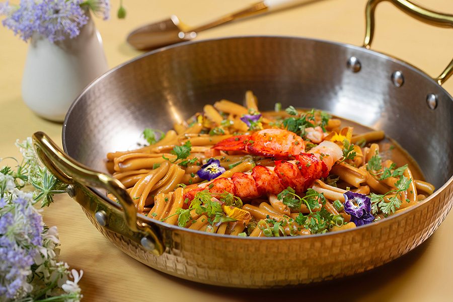 Boston Lobster Casarecce served in a decorative pan, garnished with herbs and edible flowers