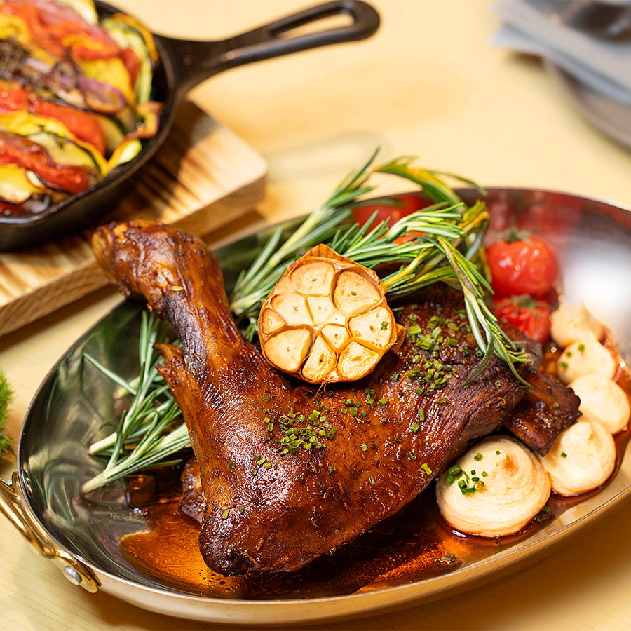 French Red Label Lamb Shoulder garnished with fresh herbs and roasted garlic
