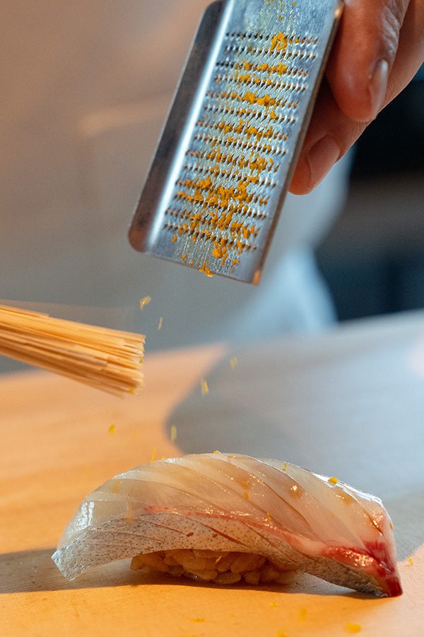 Chef preparing Sushi at Gonpachi, grating zest over a fresh piece of sushi