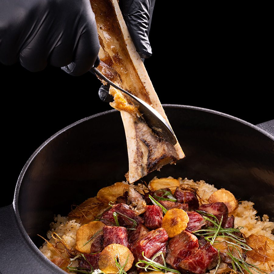 Chef serving bone marrow into a bowl of meat and rice at JJJ Korean sharing food
