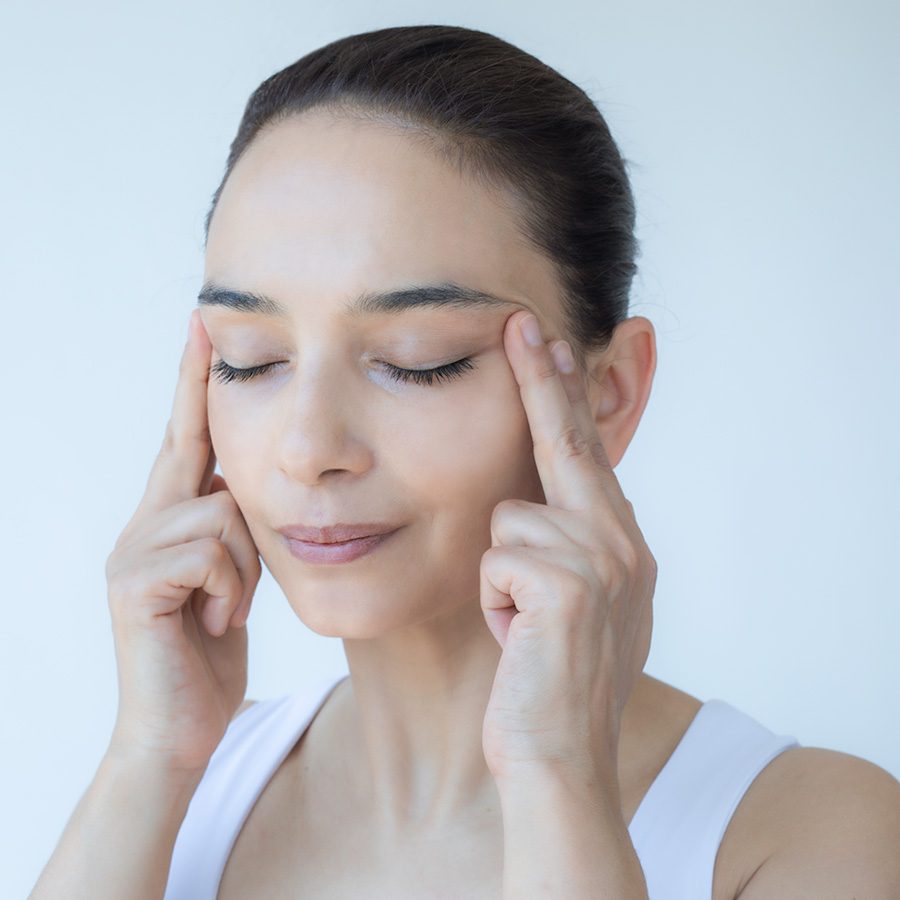 Woman performing face yoga massage near her eyes
