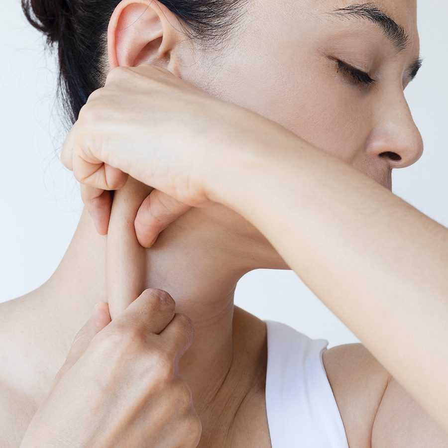 Woman performing face yoga massage on her neck