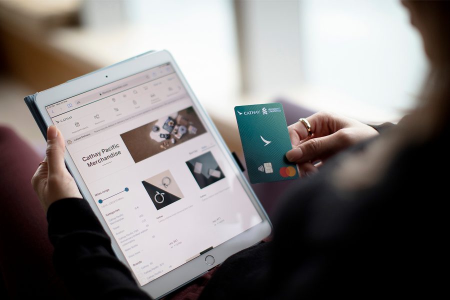 Cathay Shop open on iPad while holding the Standard Chartered Cathay Mastercard