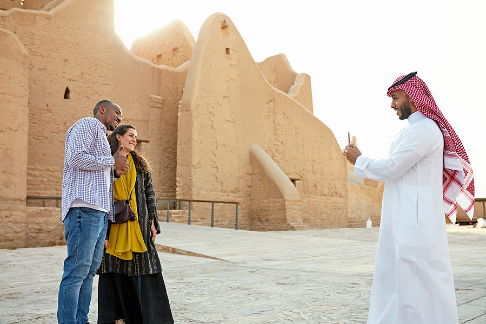 A man helps a couple of tourists to take photos in front of Salwa Palace.