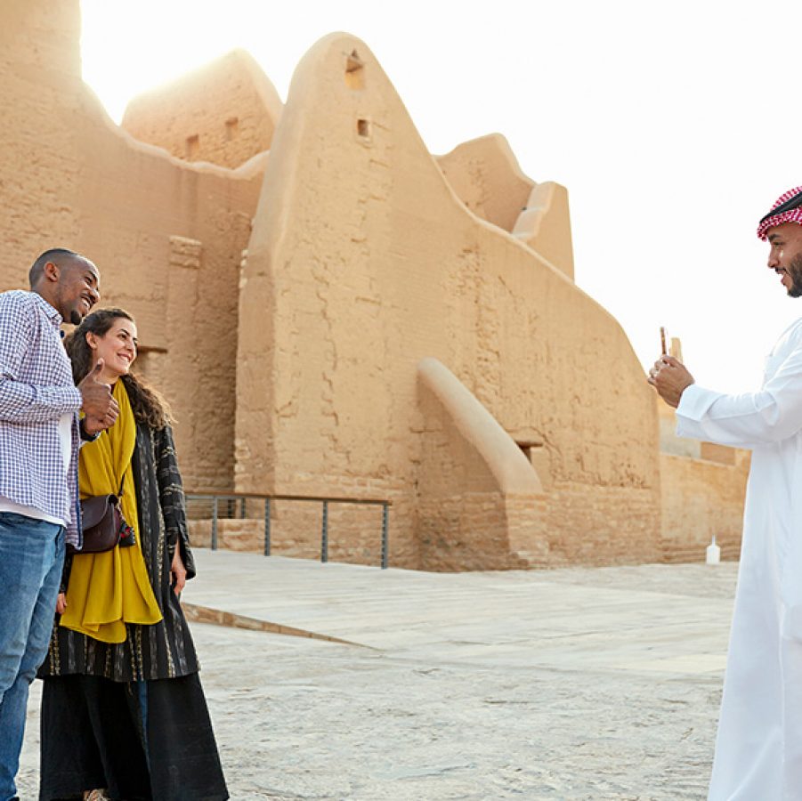 A man helps a couple of tourists to take photos in front of Salwa Palace.