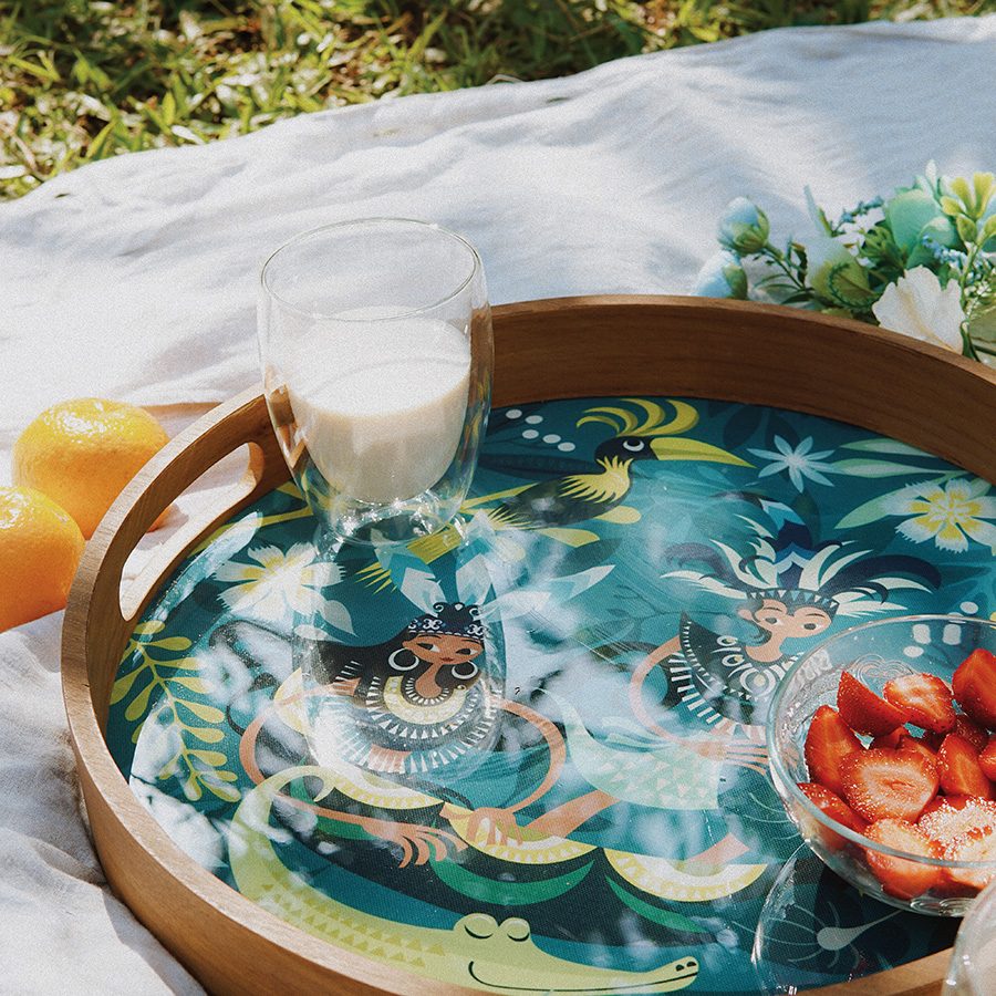 A glass of milk and a bowl of strawberries on top of a Sepiring tray