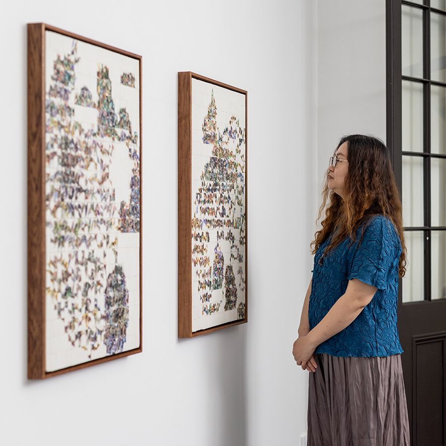 Side view of Sophie Cheung looking at her artwork.
