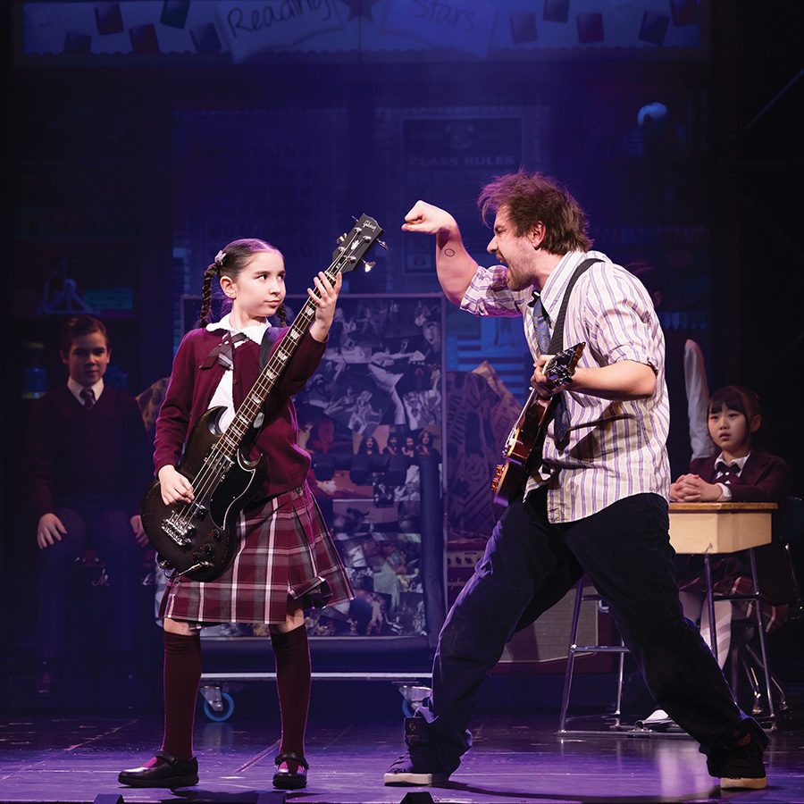 A man and a girl are rocking out on stage.