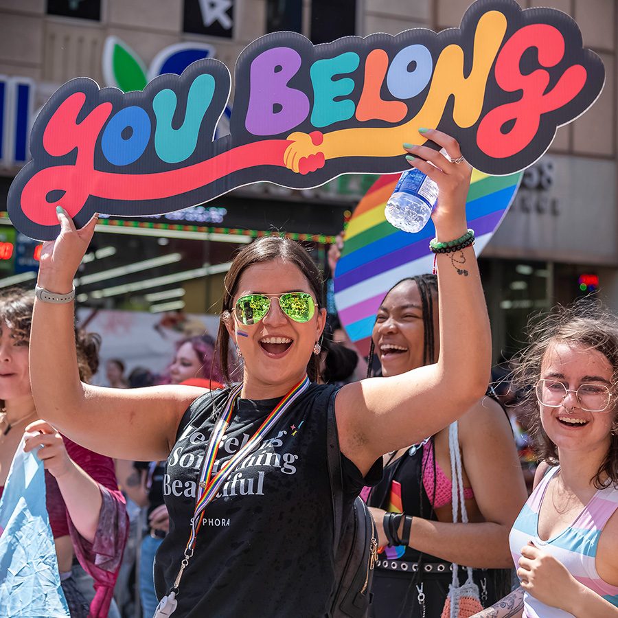 A _lady holding up a you belong sign at a pride parade in Toronto, Canada