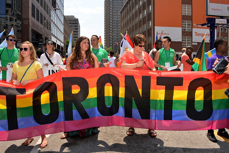 LGBTQ+ community holding up a Toronto banner at a pride parade