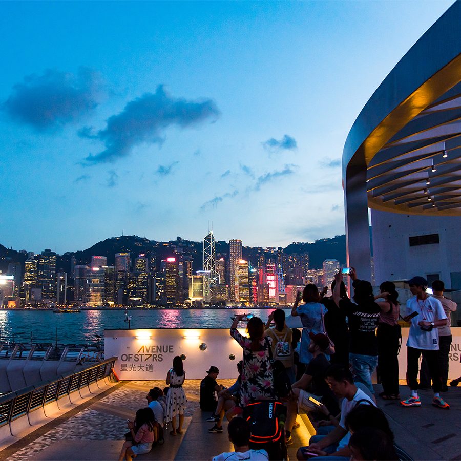 Tourists enjoying a view of Hong Kong at night.