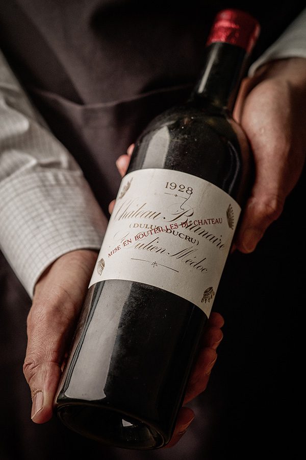 A waiter is holding a bottle of red wine