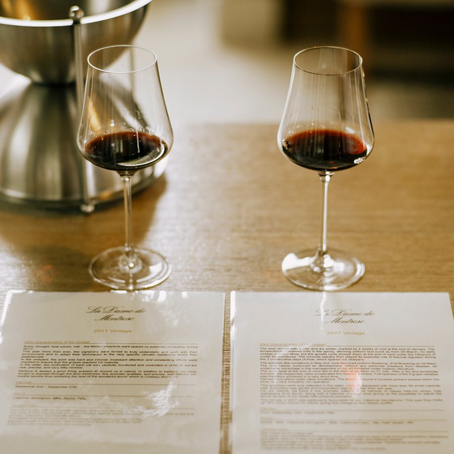 Two glasses of red wine and two pieces of paper.