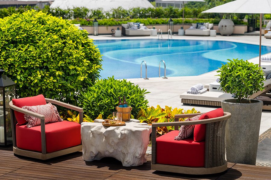 A pool at Regent Hong Kong with two red chairs nearby
