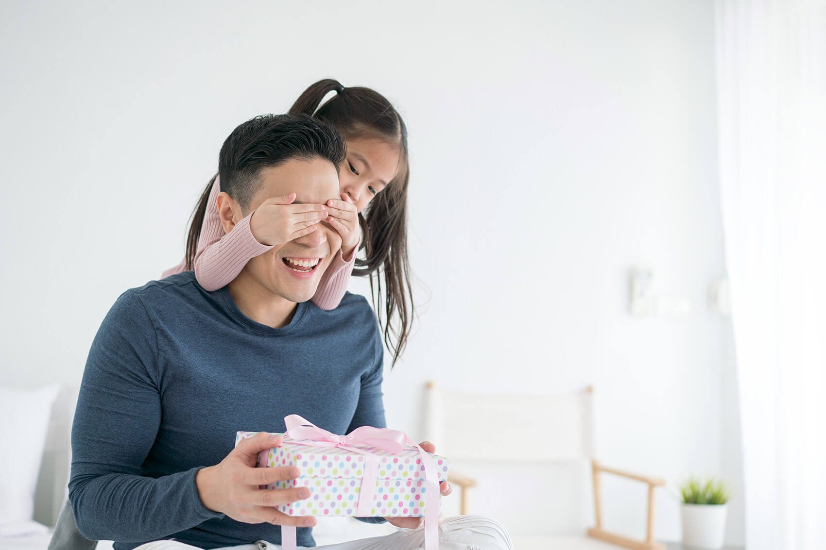 A daughter covering her father's eyes to surprise him