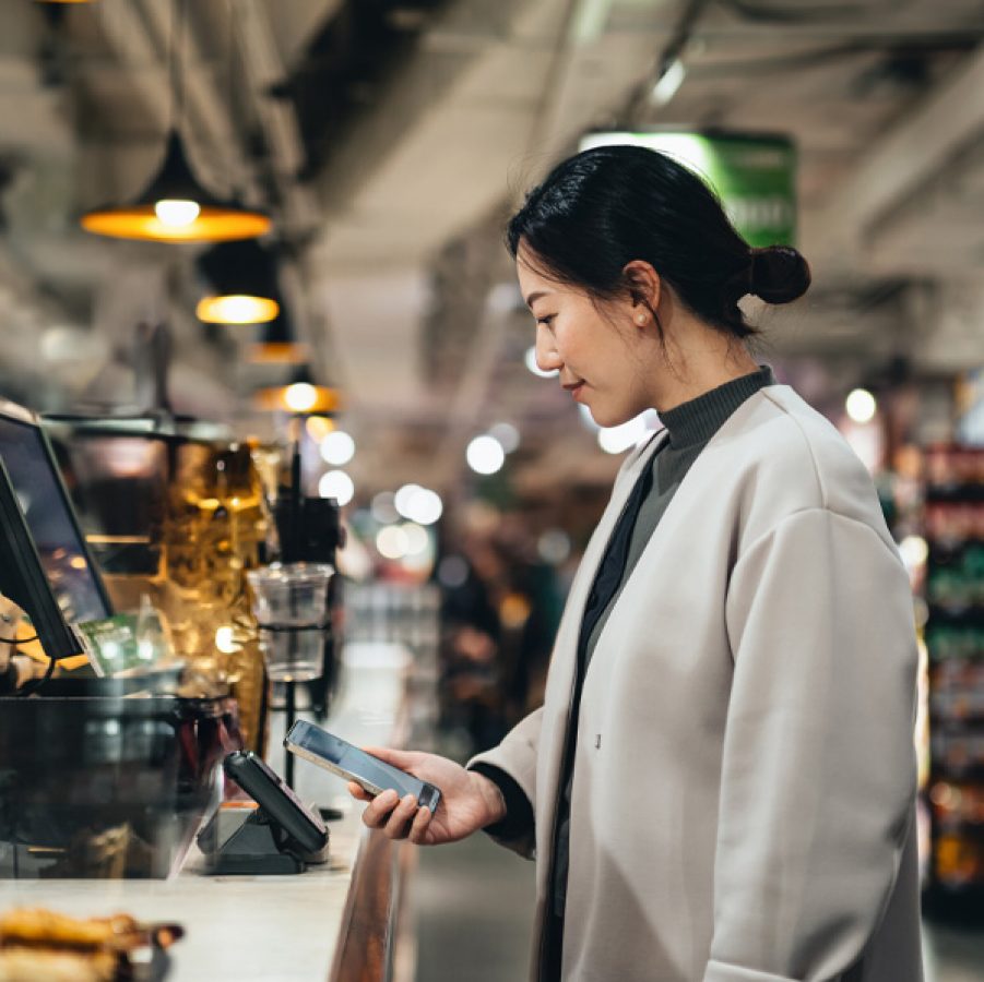 Woman checking out at cashier-less till in shop