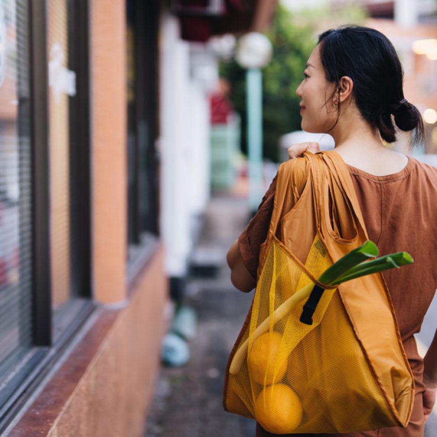 Woman walking down street with sustainable bag full of groceries