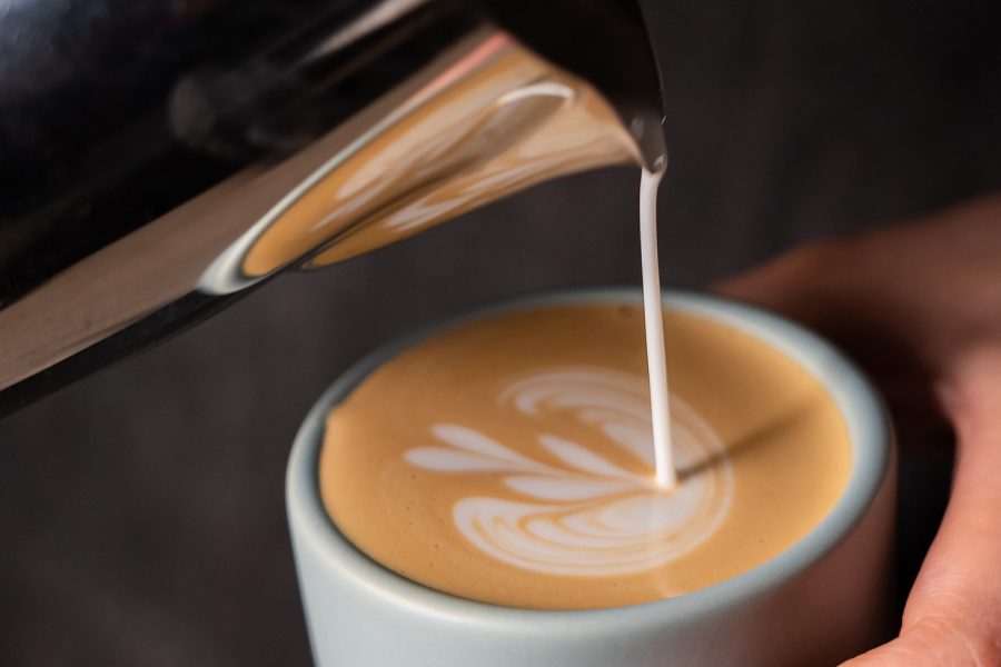 Cupping Room hot latte, a closeup image of a barista pouring hot milk into a cup of coffee