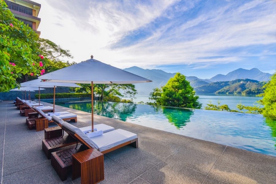 A view of the clear sky, mountain and lake from the outdoor swimming pool of The Lalu, Sun Moon Lake hotel in Nantou County, Taiwan