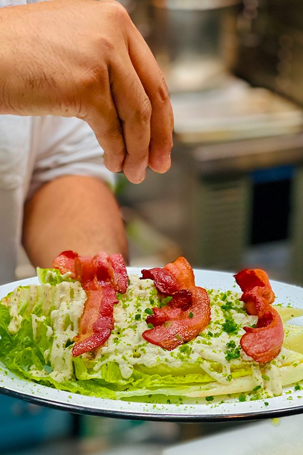 A chef is preparing a dish of meat.