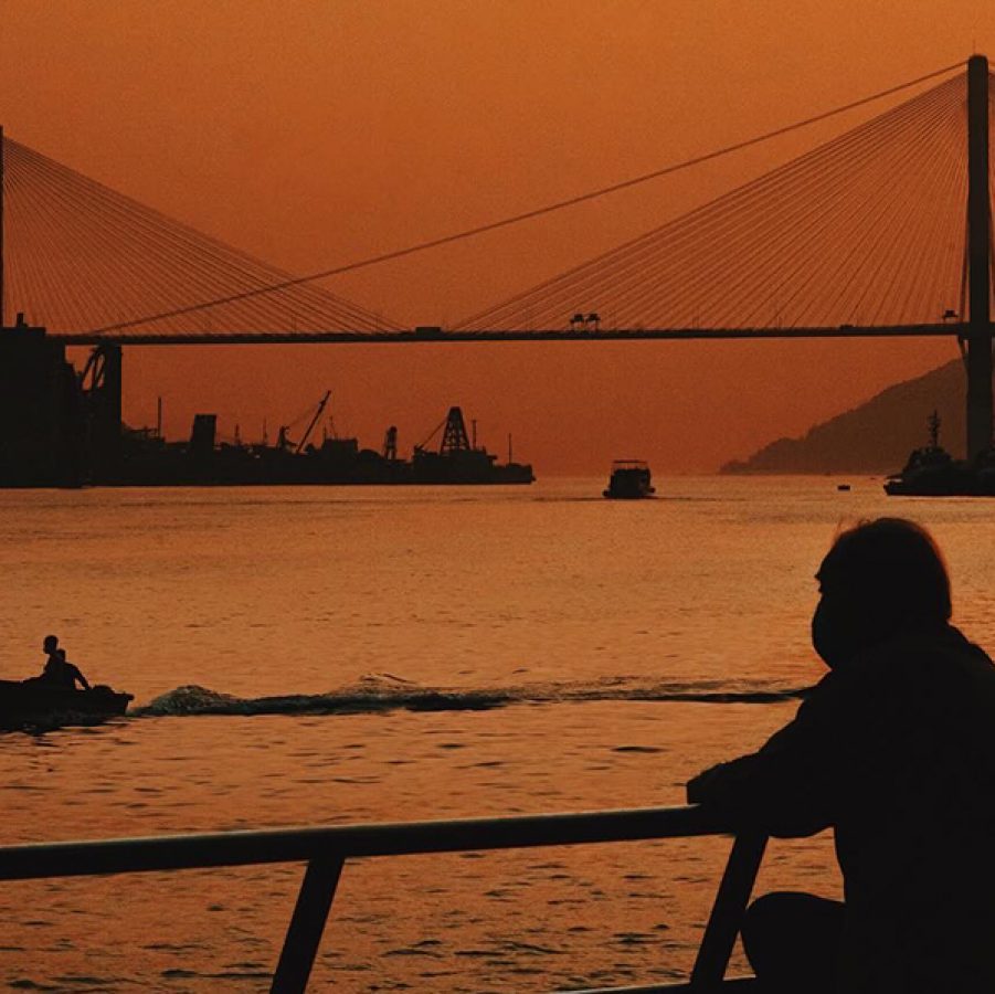 The back of a person standing by the river at dusk.