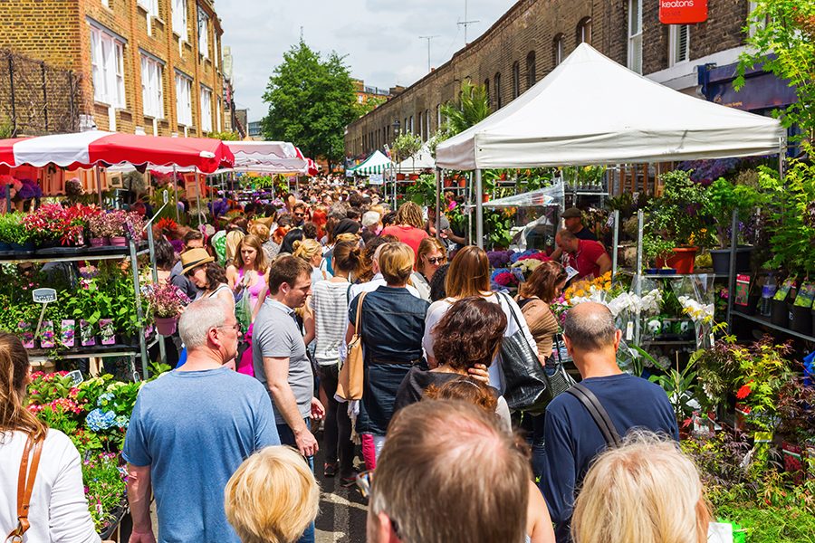 People walking through the Flower Market on Columbia Road in London.
