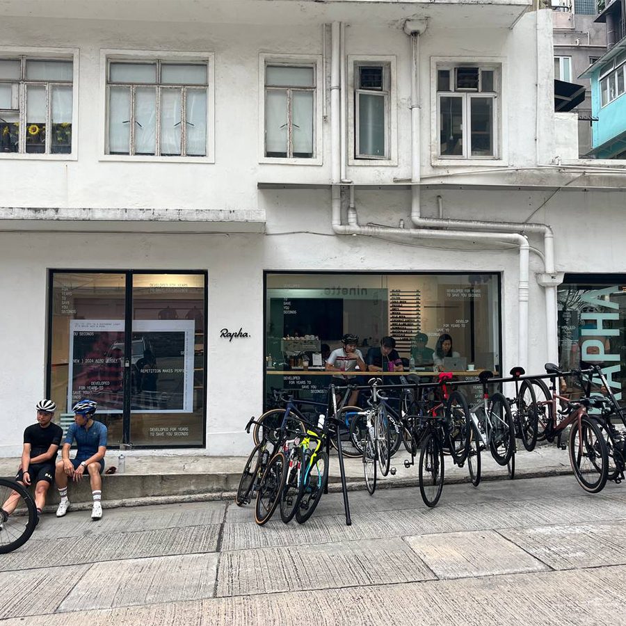 Two cyclists sitting outside Rapha Hong Kong Clubhouse with bicycles parked at the entrance