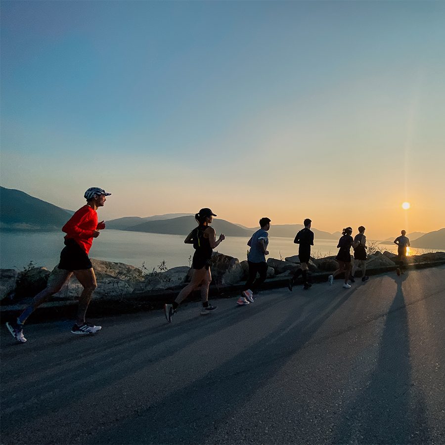 A group people jogging on the road by the sea at sunset