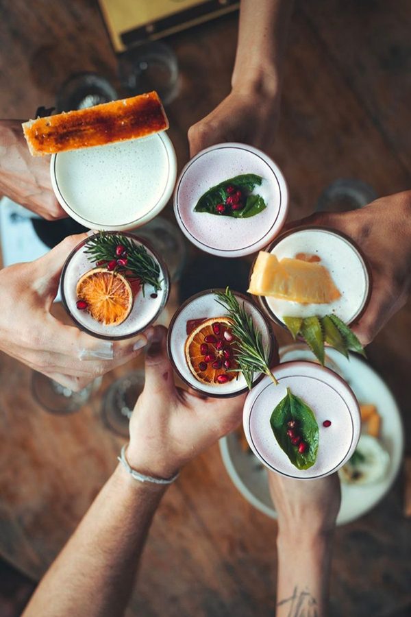 A top view of a group holding six colorful cocktails at Smoke & Bitters, Sri Lanka