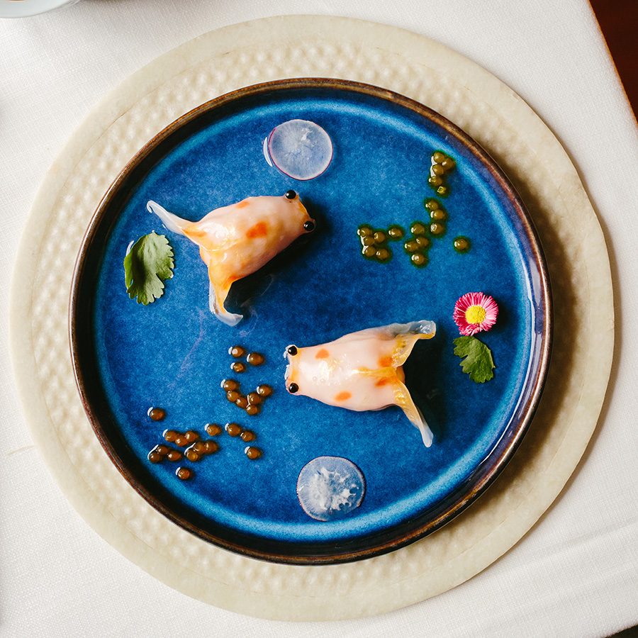 Dim sum designed to look like goldfish served on a blue plate 