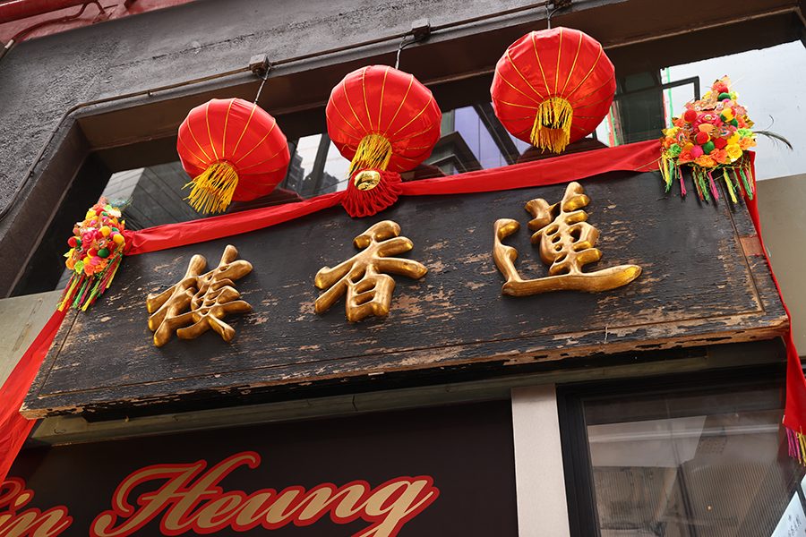 A sign with Chinese characters and red lanterns hanging above it at the entrance of a restaurant 