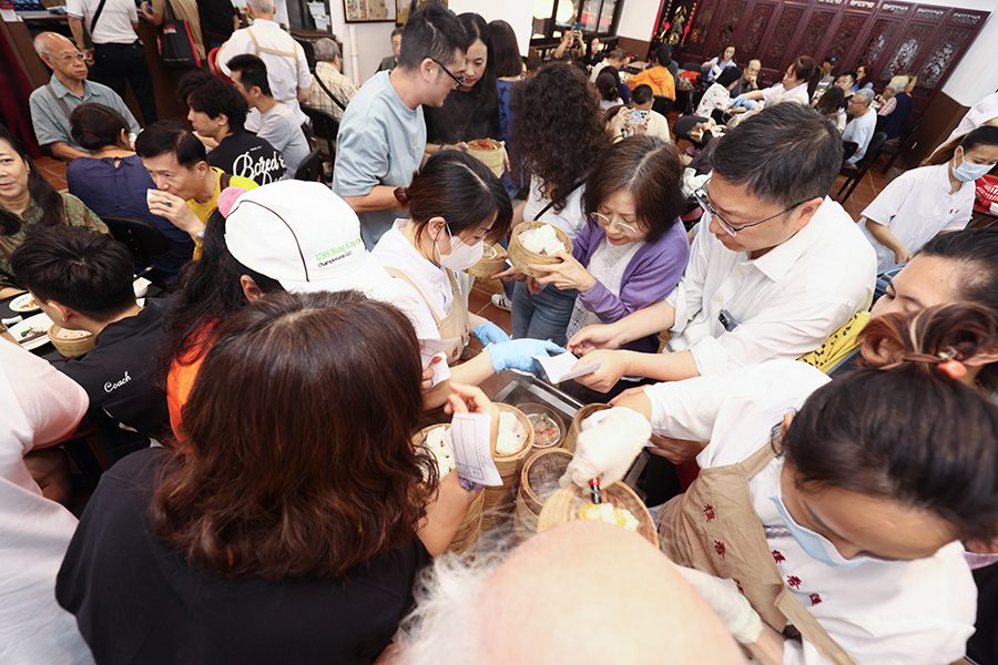 People take bamboo baskets of food from a trolley at a busy restaurant