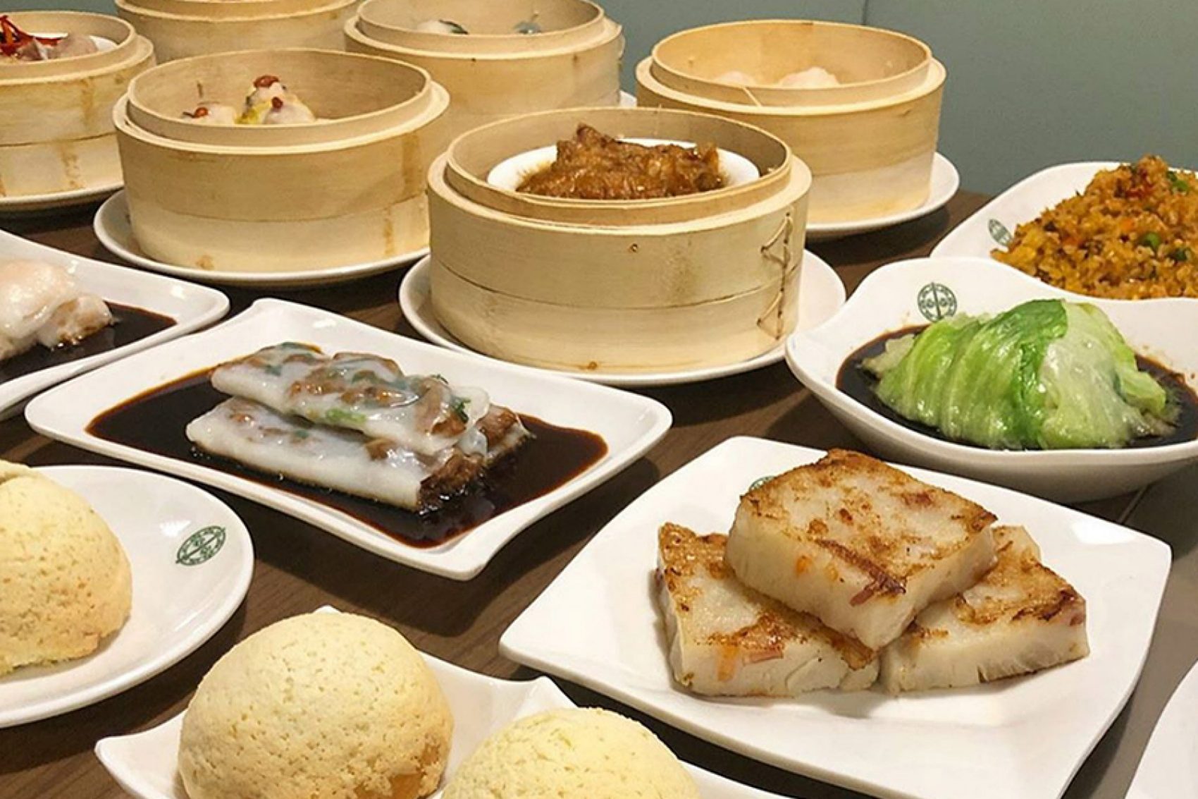 A table of assorted dim sum dishes on plates and in bamboo steamers 