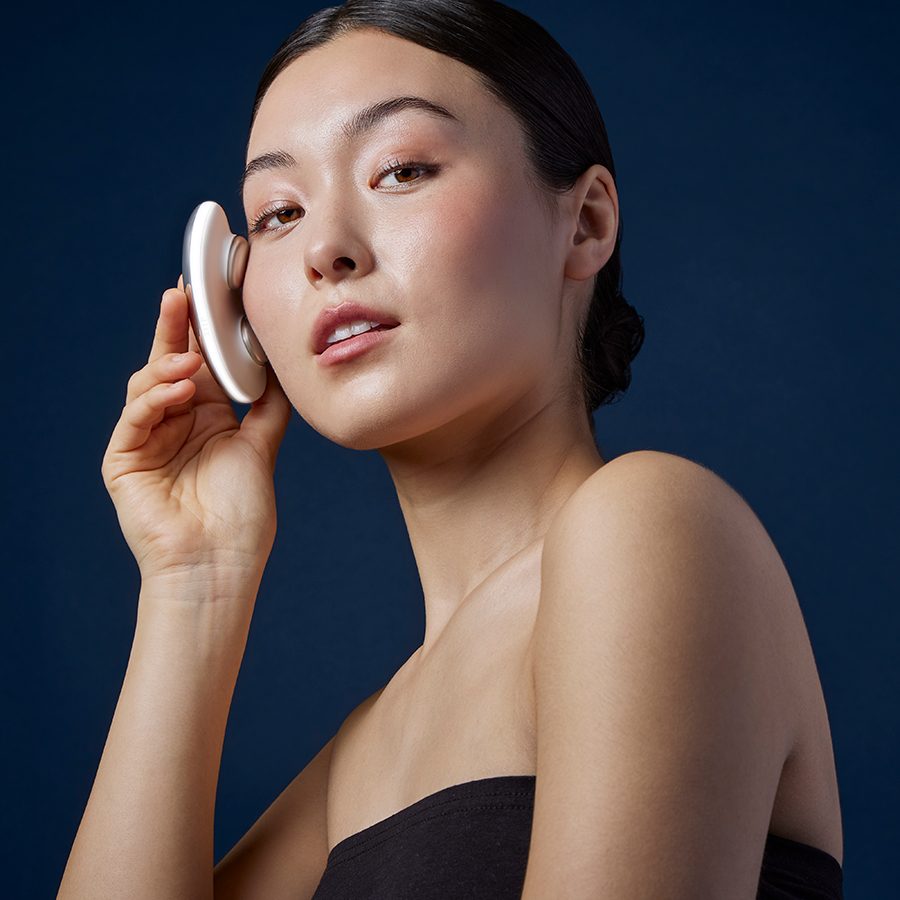 An Asian model using the pocket-size Ziip Halo high-tech beauty device on her face