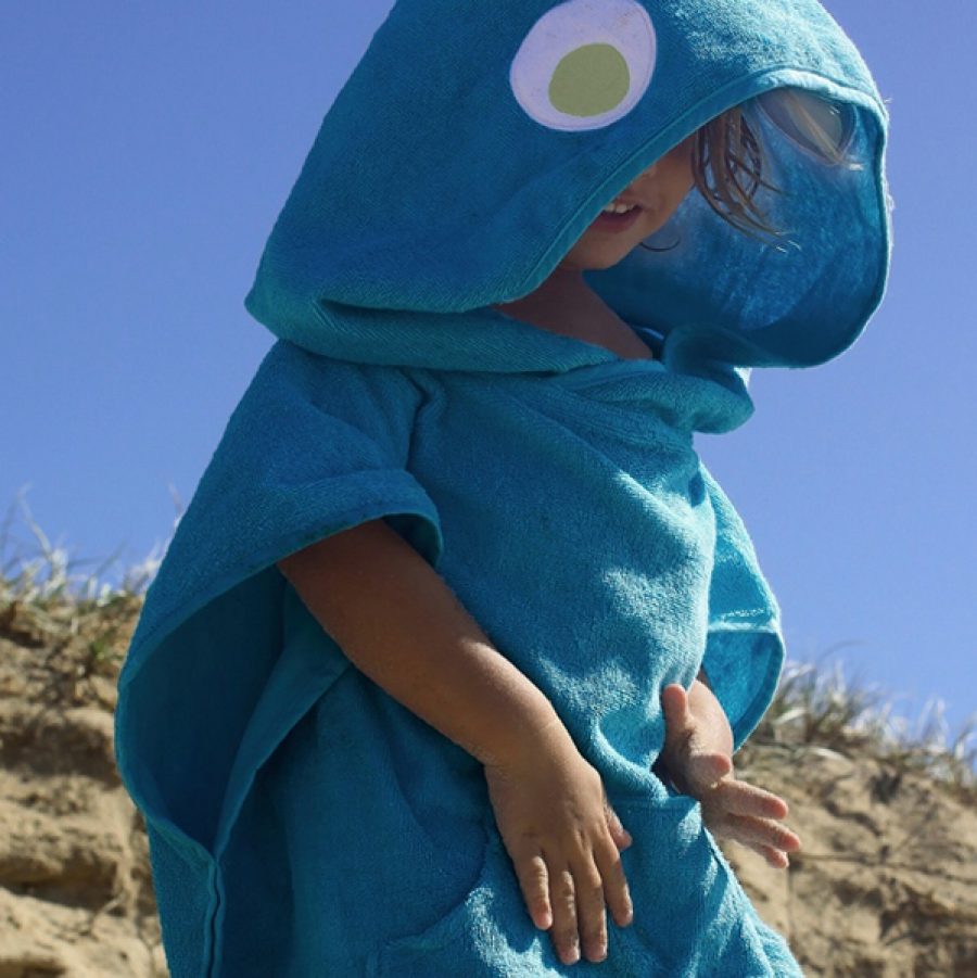 A child hides his face in a dinosaur-shaped towel.
