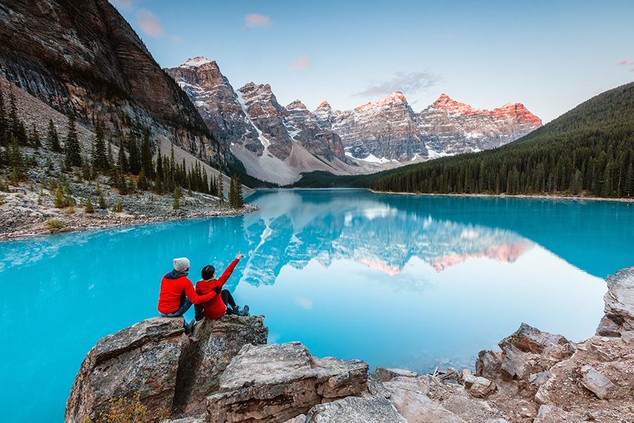 A couple sitting in front of a fjord looking at Banff National Park