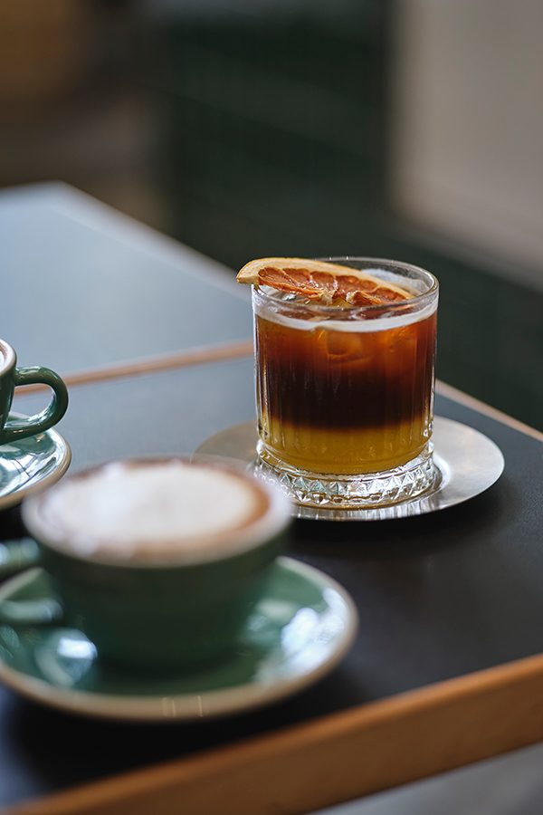 A cappuccino and an iced americano with an orange slice on a table at Colour Brown x GO.ON Space in Sham Shui Po, Hong Kong.