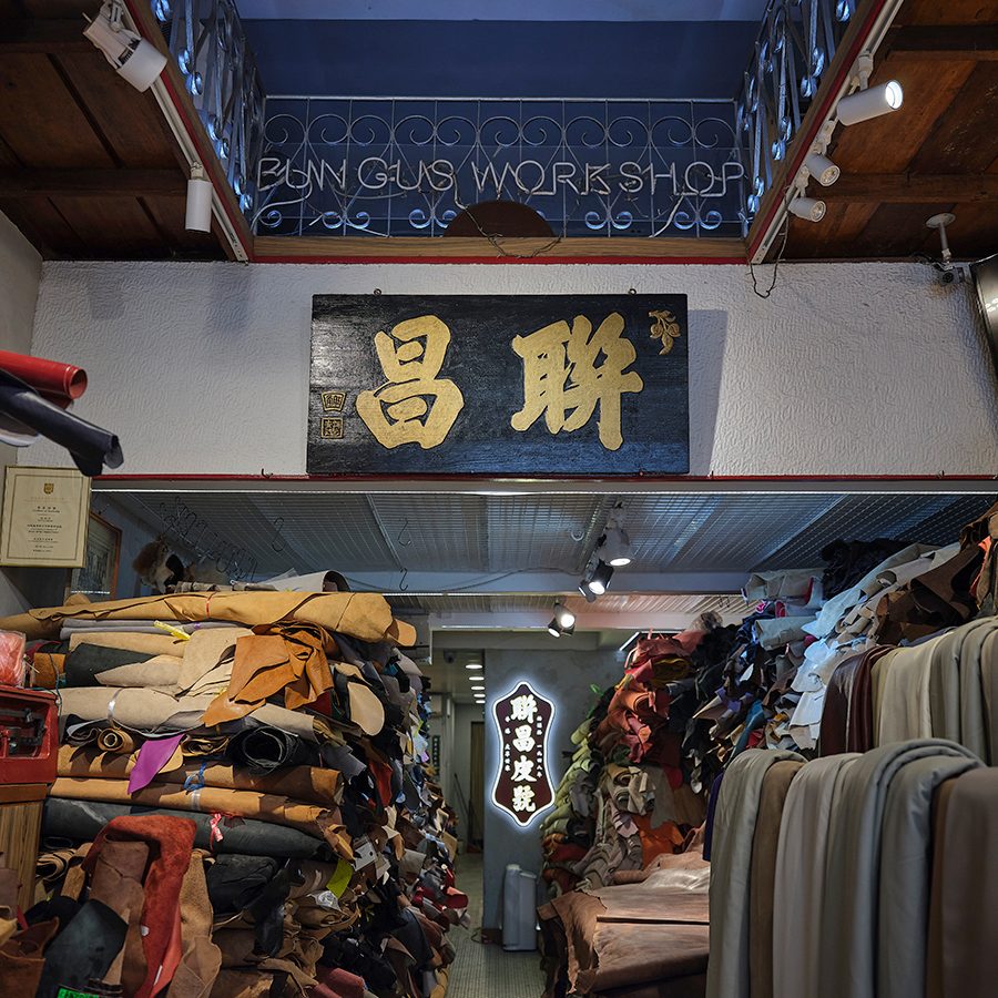 Stacks of leather hides at Luen Cheong Leather Co. in Sham Shui Po, Hong Kong. A black sign with the shop’s name in Chinese in gold hangs on a wall.