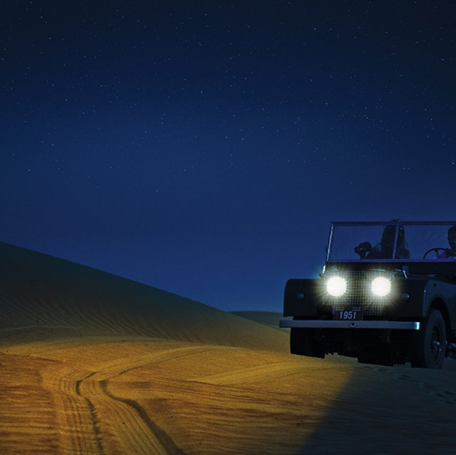 A man driving a jeep in the dessert on a sand dune in Dubai, UAE
