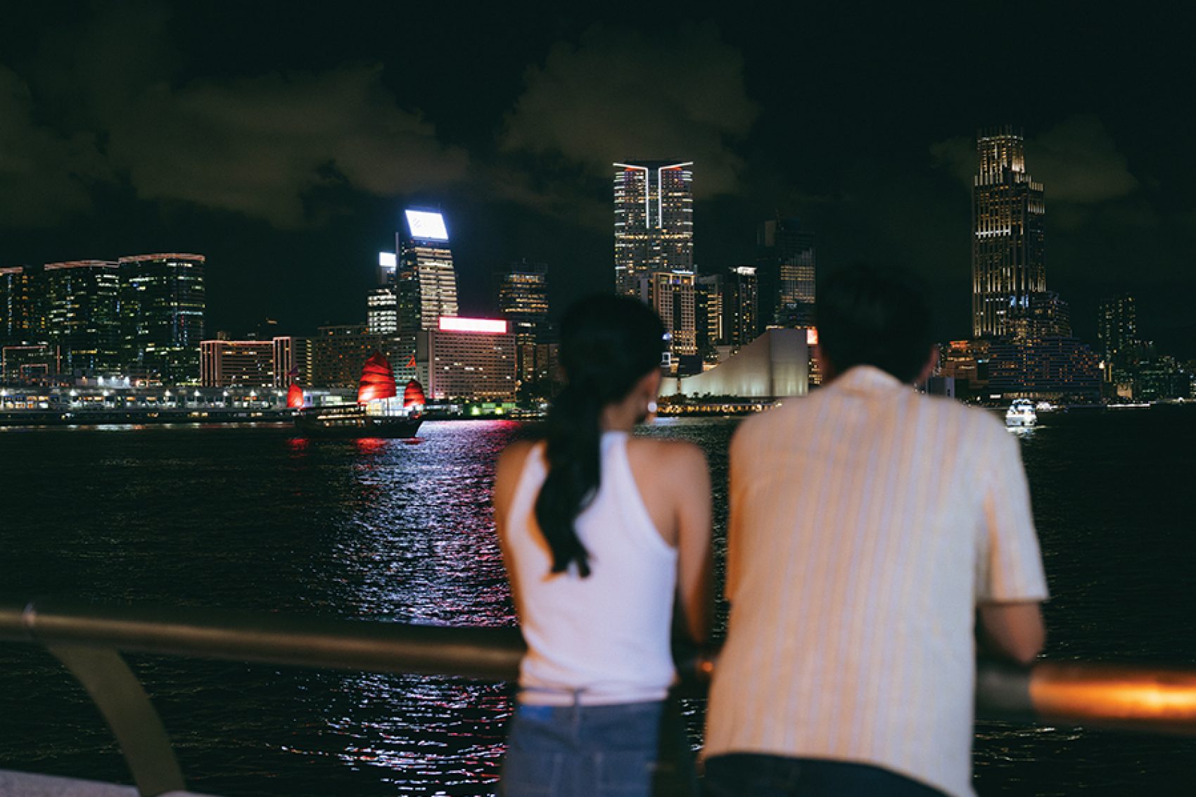 A couple, man and woman, on a date at night looking out to Victoria Harbour