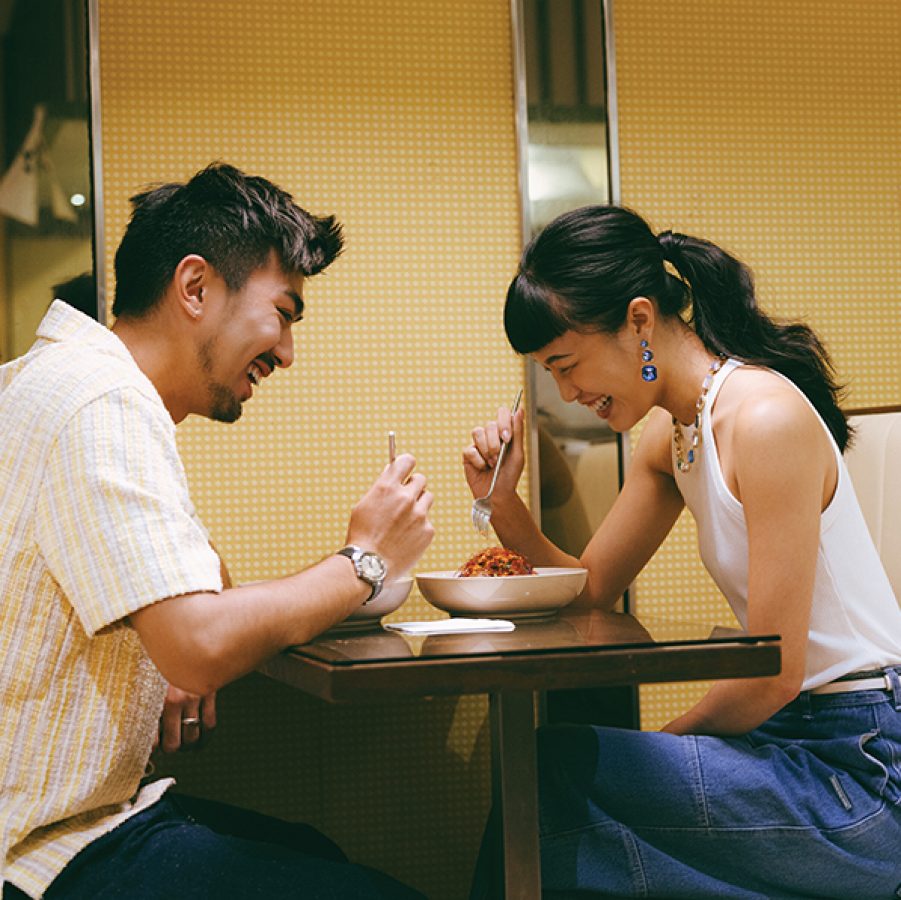 A couple of man and woman eating and laughing at a cha chaan teng in Hong Kong