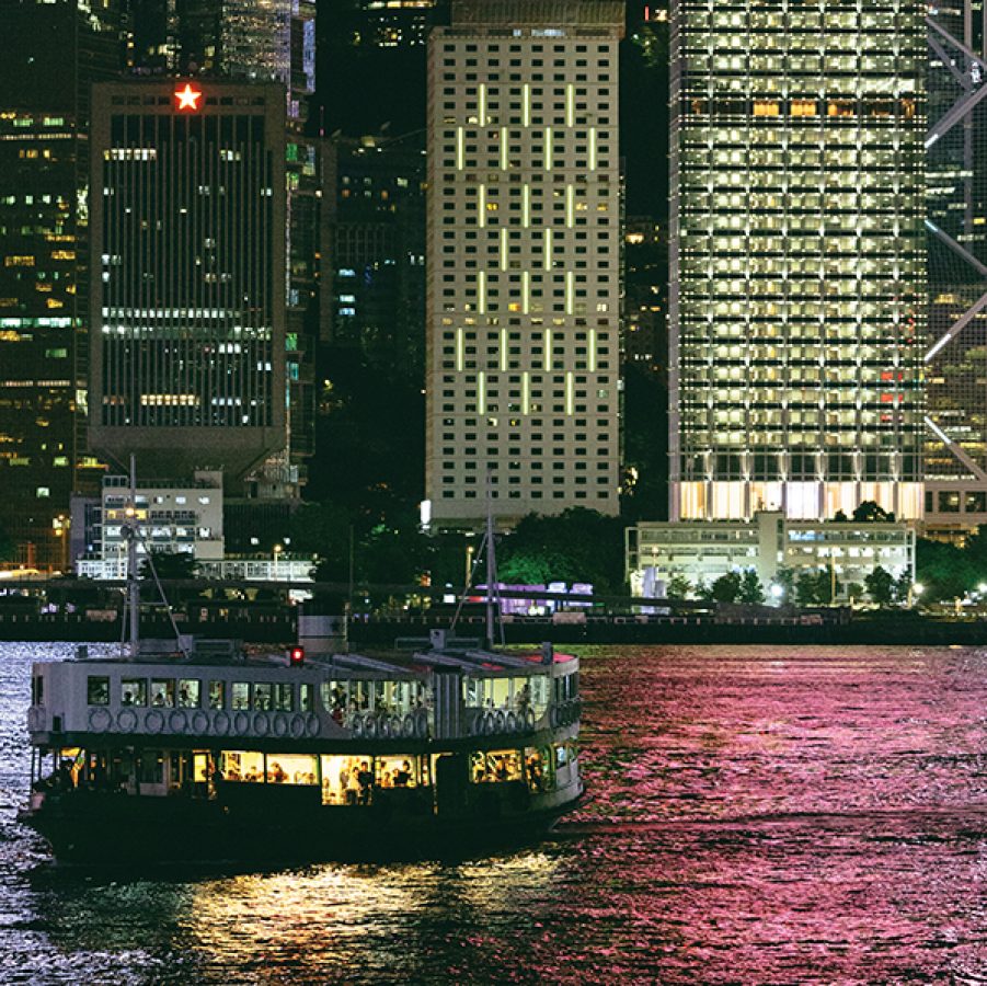 A view of a star ferry cross Victoria Harbour at night and Hong Kong's city lights reflecting on the water