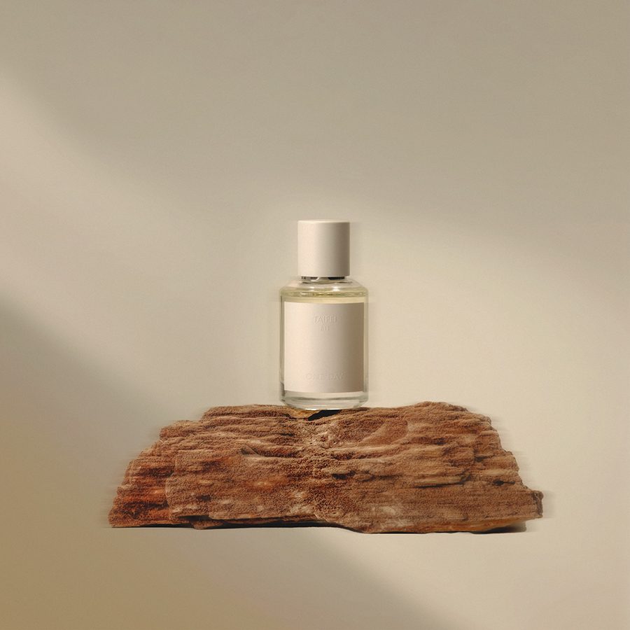 A display of Taipei One Day fragrance in a glass bottle on a wood plank