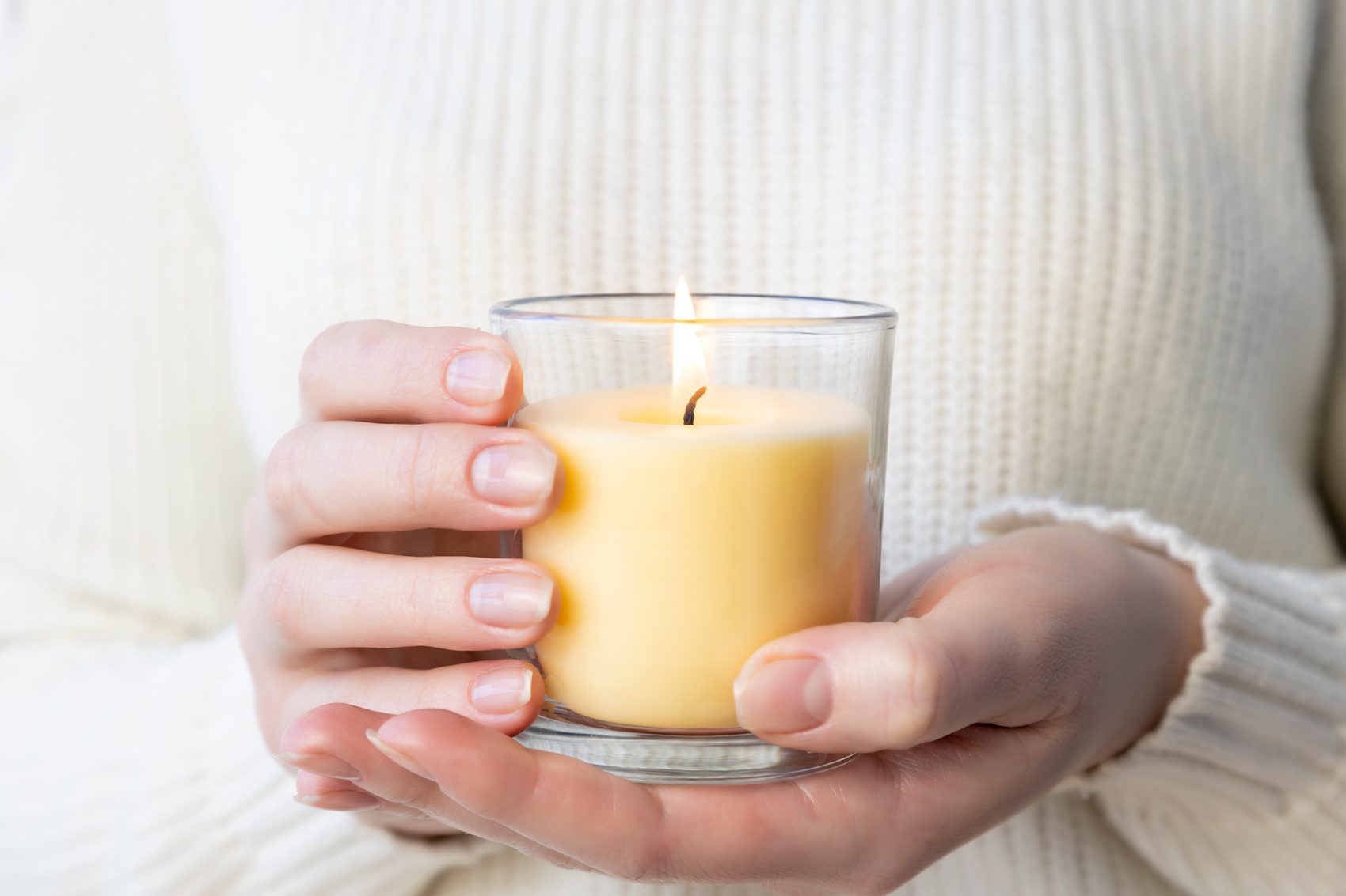 Woman holding a lit yellow scented candle